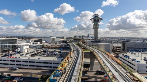 Concrete pathways and guide rails are installed on the People Mover train guideway over World Way West.